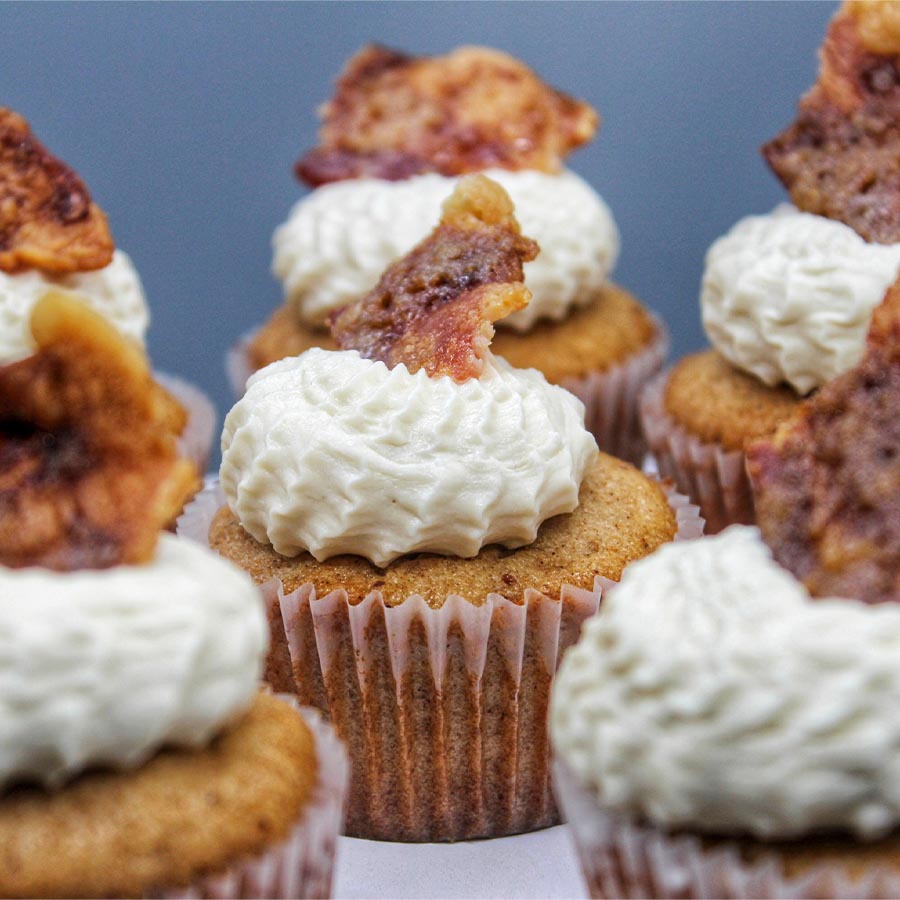 close up of white icing cupcakes with a piece of bacon on top